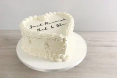 a white vintage heart shaped cake, with white piping and lace